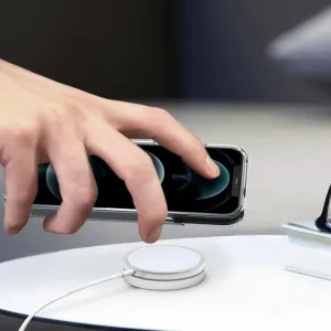 Just Mobile aluDisc mini magnetische Wandhalterung mit einem iPhone, das über einem runden Ladepad auf einer Tischplatte gehalten wird