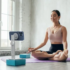 Just Mobile AluDisc Pro Telefonständer mit einem Smartphone neben einer Frau, die auf einer Yogamatte meditiert.