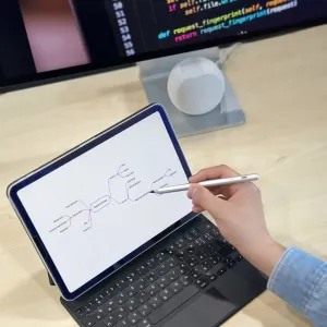 Just Mobile Eingabestift für iPad in Silber, über einem Tablet auf einer Tastaturhülle zum Notieren und Zeichnen gehalten