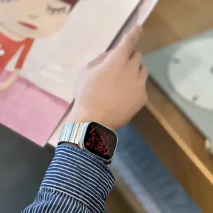 Just Mobile Titan-Uhrenarmband an der Apple Watch Ultra, getragen an einem Handgelenk mit silbernem Gliederarmband-Design.