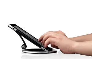 Support réglable Just Mobile Encore pour iPad maintenant une tablette sur une base argentée inclinée, avec interaction tactile de la main