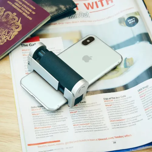 Just Mobile Shutter Grip 2 nutitelefonihoidik iPhone’il, näidatud koos Bluetooth-päästikuga ajakirjal