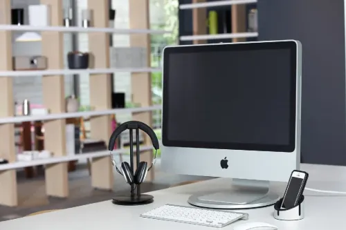 Just Mobile AluDisc, rund aluminiumplatta med låg profil under bildskärmens fot på skrivbord, synlig som slät, cirkulär bas.