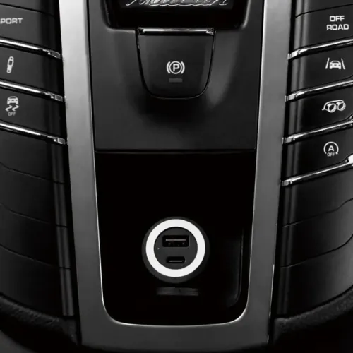 Rund profilert billader montert i bilens midtkonsoll, med USB-A- og USB-C-port, sølvring og grønn indikator.