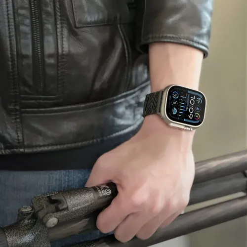Kulfiberarmbånd til Apple Watch; mørkt bånd med geometrisk mønster og lav profil, fastgjort til rektangulær urskive.