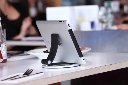 Just Mobile Encore iPad-ställ i aluminium med rund bas och ledad svart arm, håller en iPad horisontellt på ett bord i sidovy.