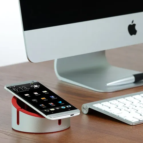 Just Mobile AluCup Grande red aluminum phone stand with cable groove, holding a smartphone on a desk