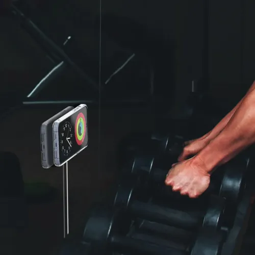 AluDisc mini wall mount holds an iPhone against a mirror; round, thin disk behind the phone with cable running straight down.