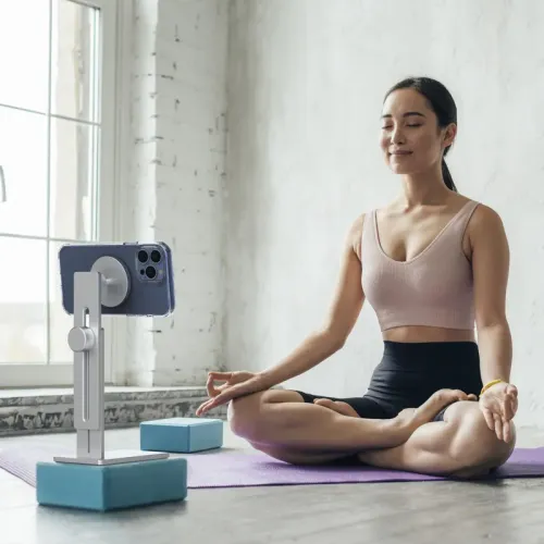 iPhone stand with magnetic head, height slider and square base, holds a lying phone on yoga block on mat by window.